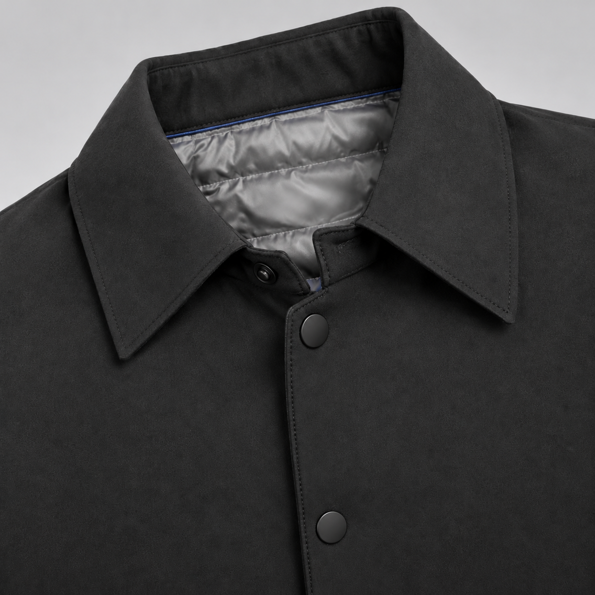 Close-up of black mac coat collar, snap buttons and quilted lining